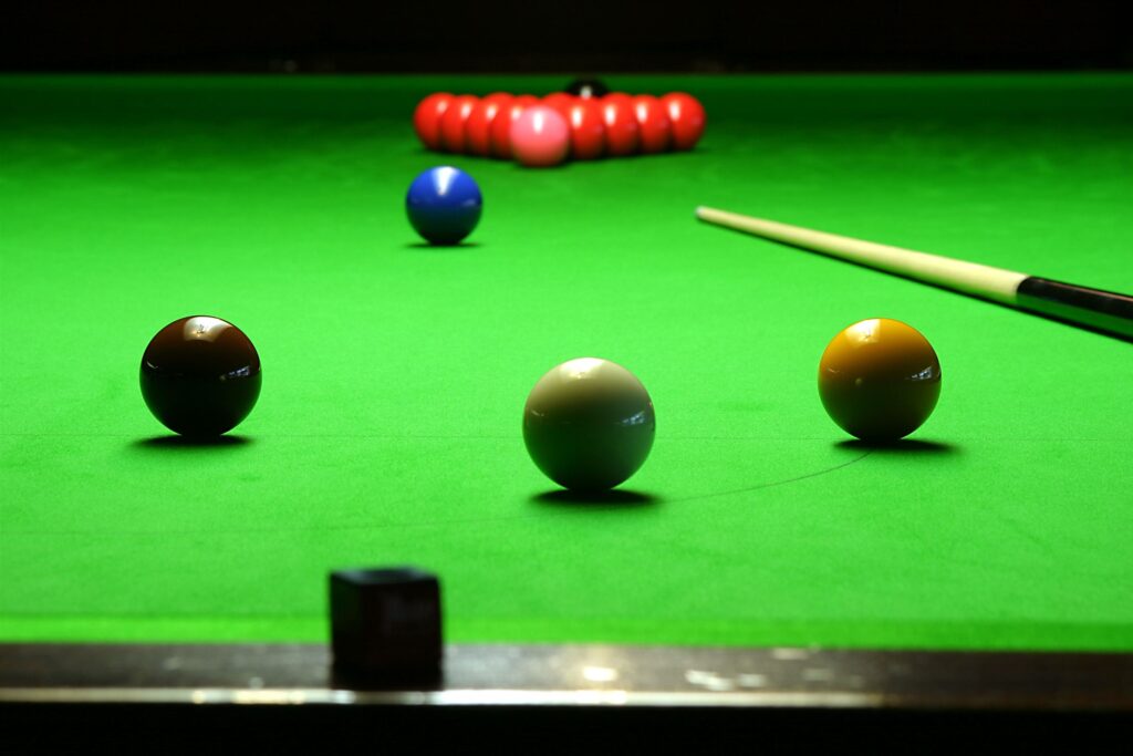 Farbige Snookerkugeln und Queue auf dem grünen Tuch