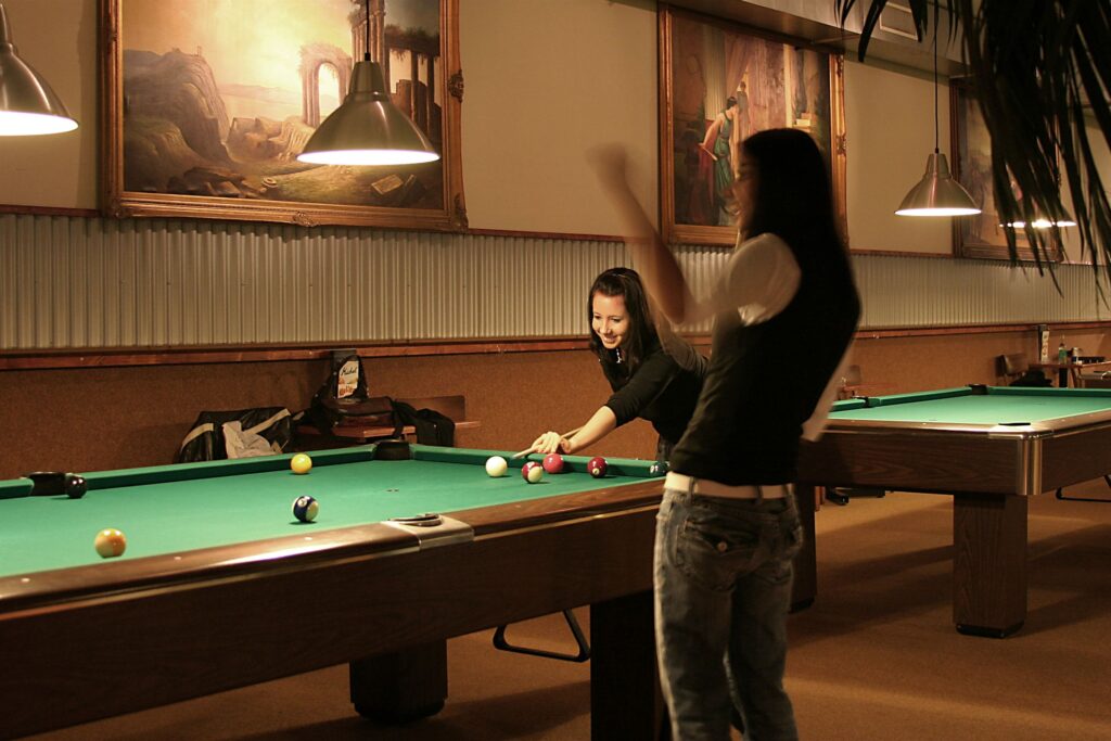 Zwei Frauen spielen Poolbillard, eine setzt zum Stoss an